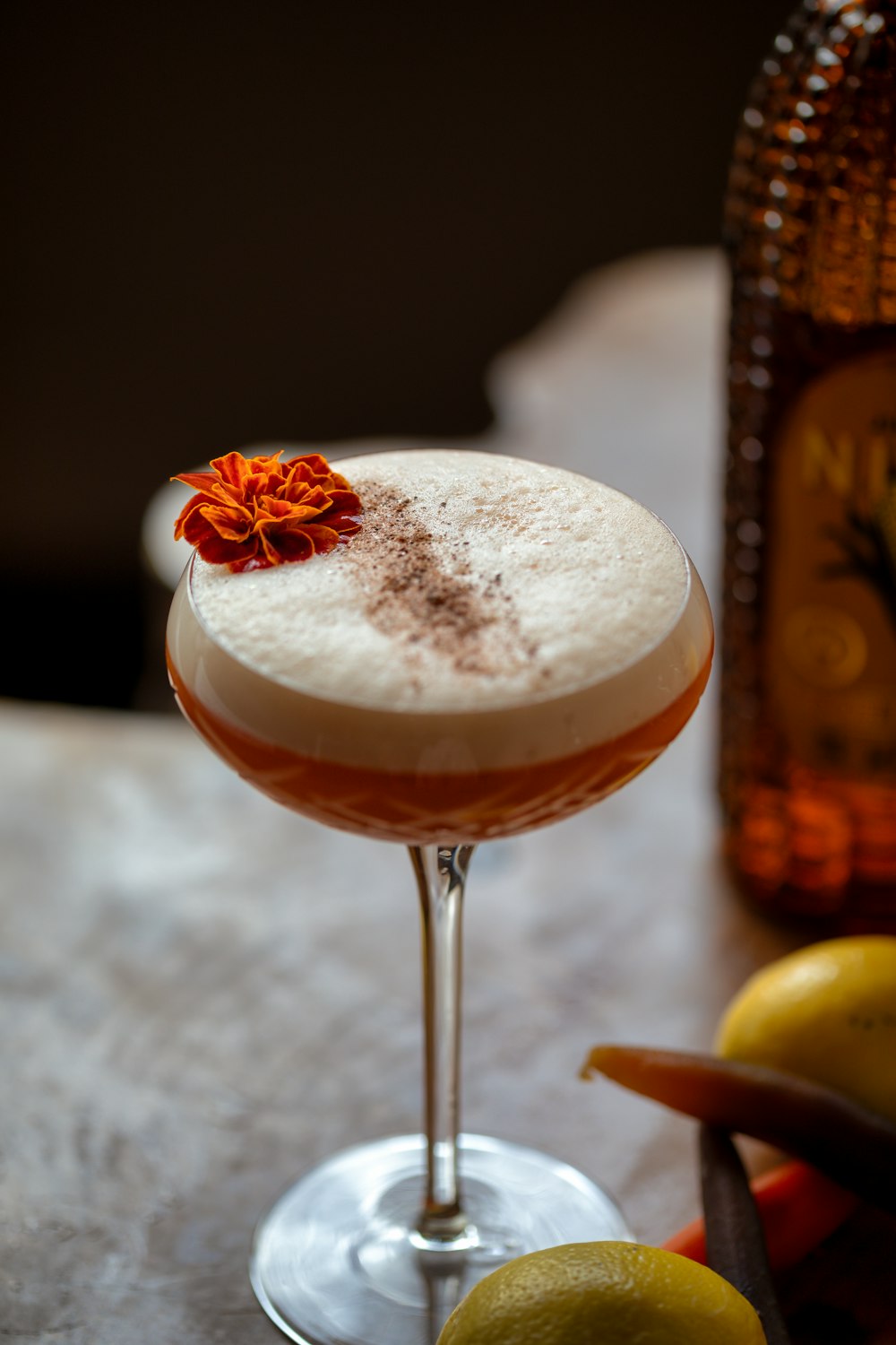 a cocktail sitting on a table next to a bottle of alcohol