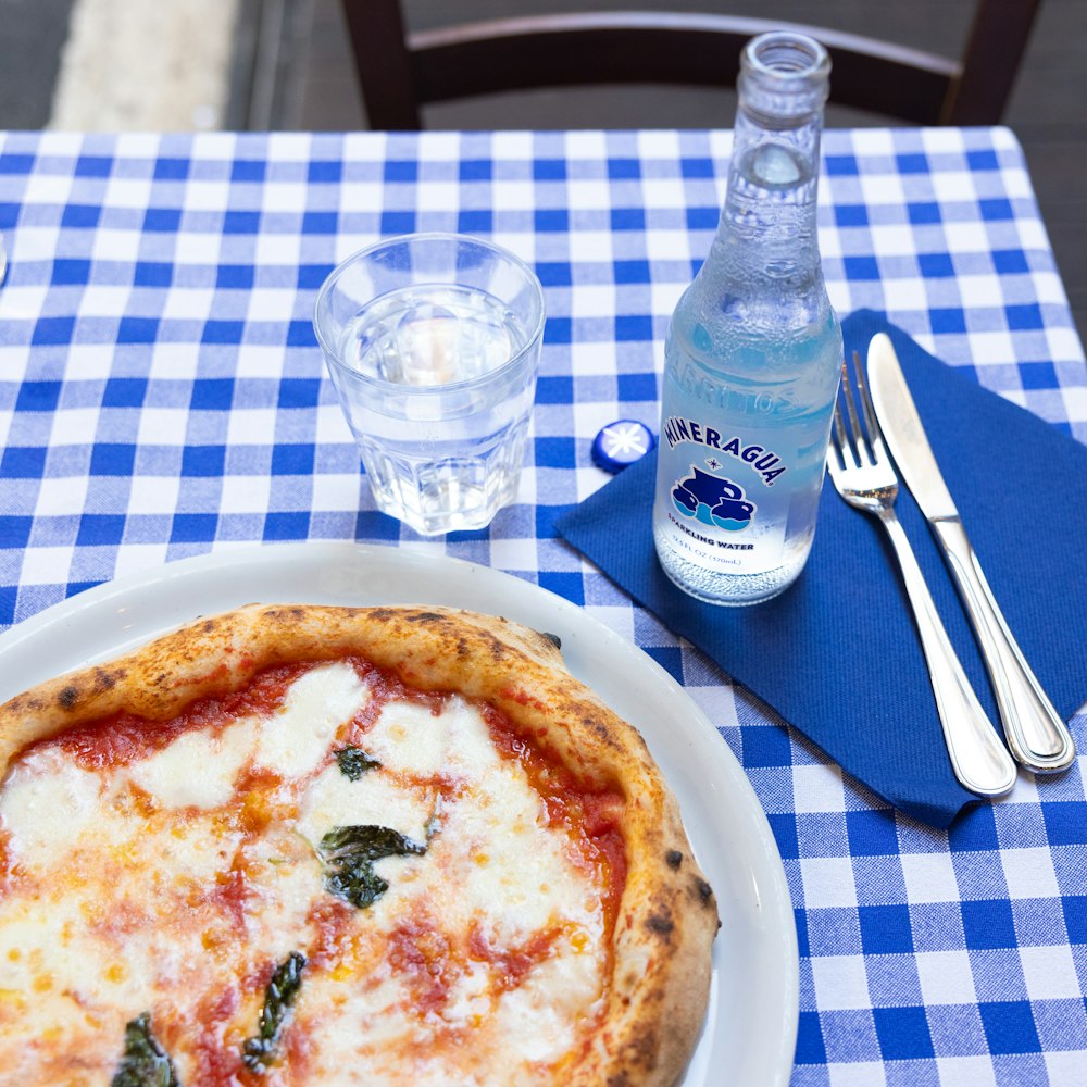 a plate of pizza and a bottle of water on a table
