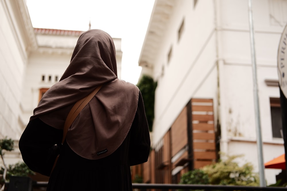 a woman wearing a brown shawl walking down a street