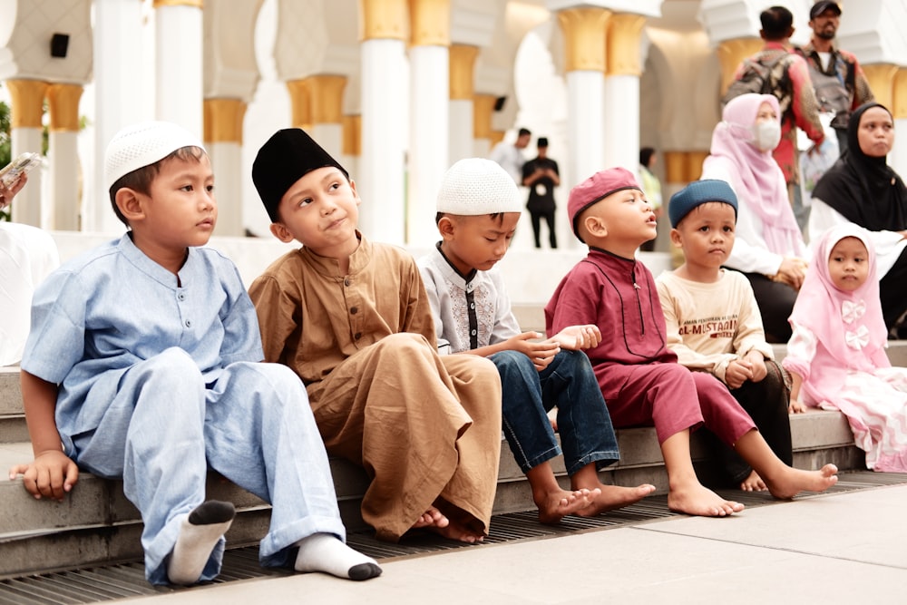 a group of children sitting on a ledge