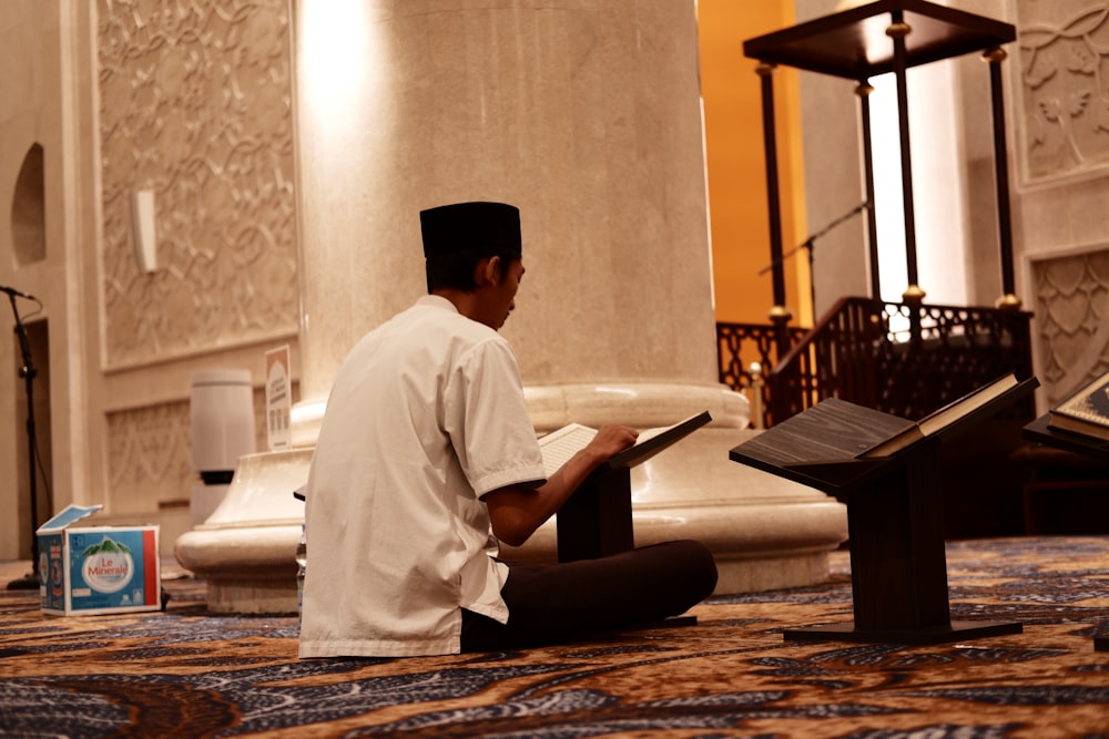 a man sitting on the floor reading a book