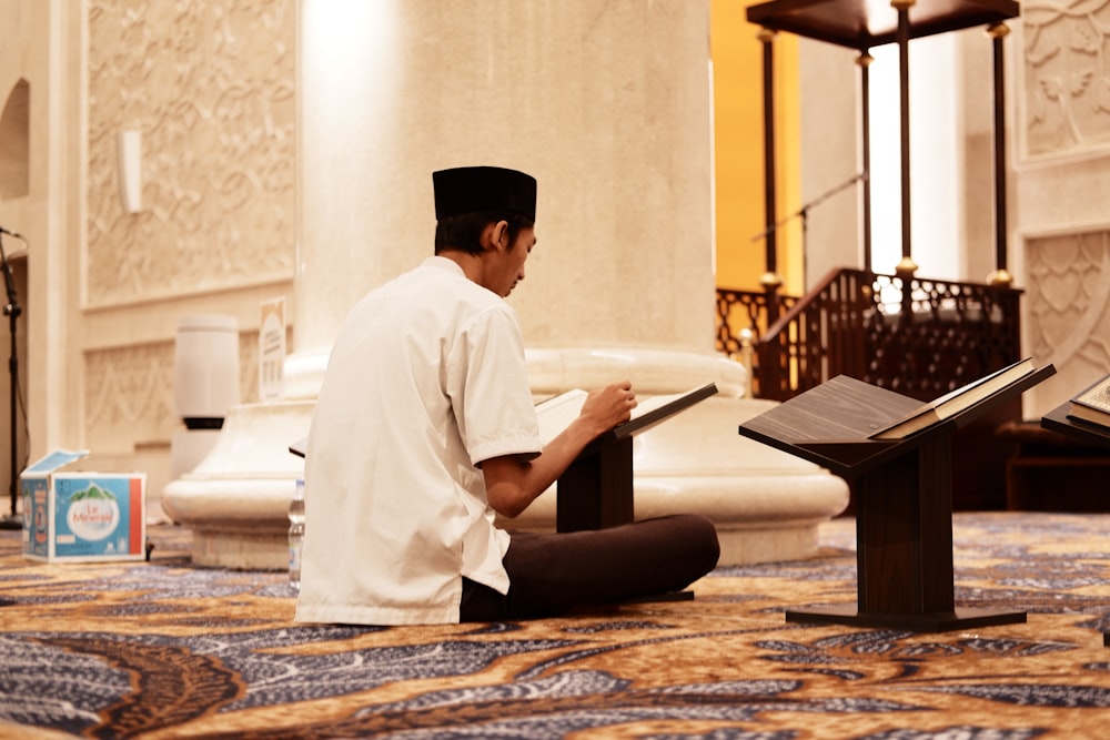 a man sitting on the floor reading a book