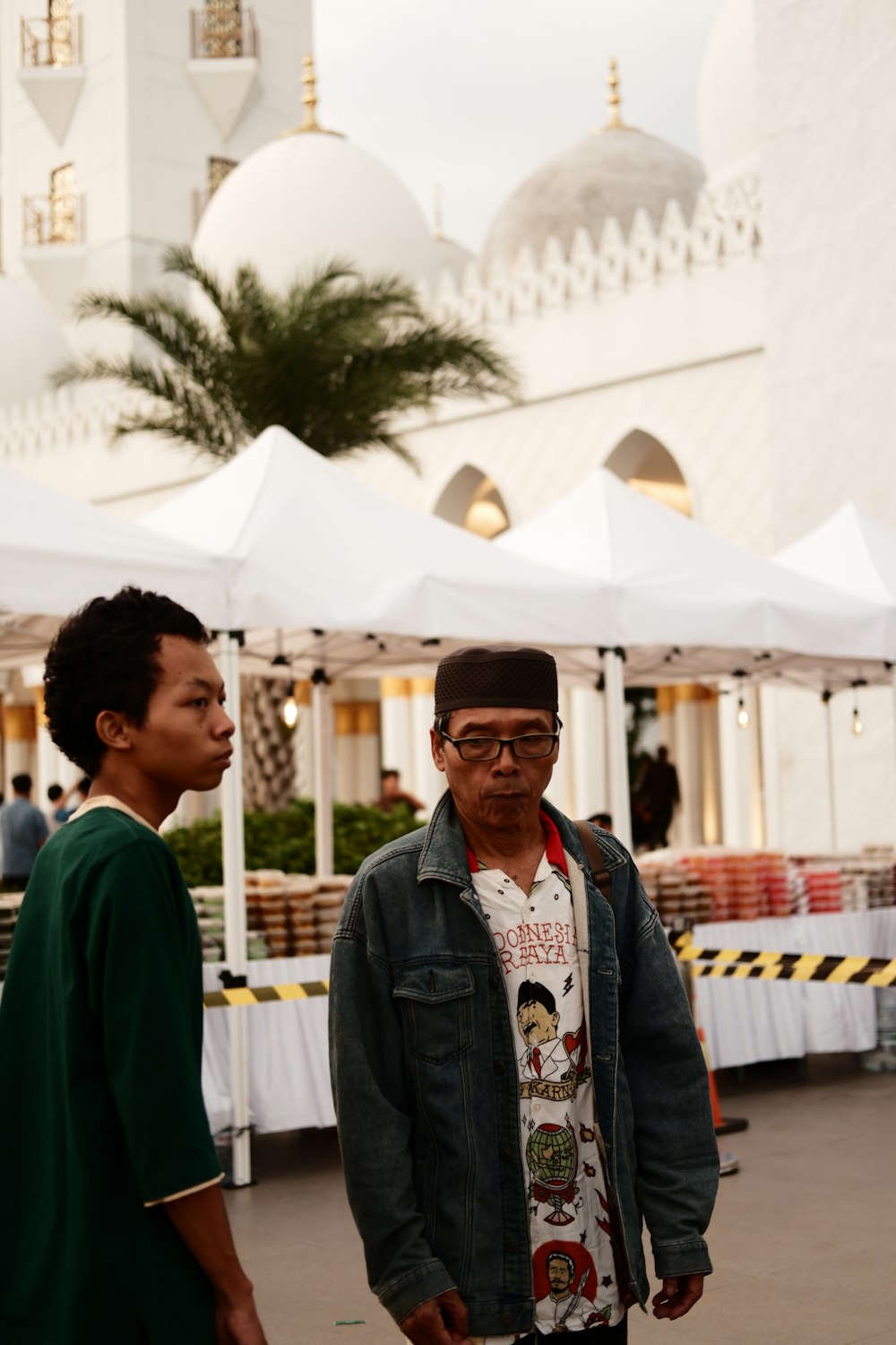 a man standing next to another man in front of a white building