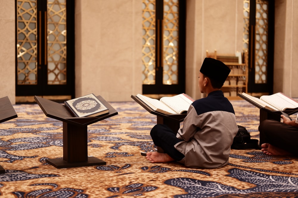 a man sitting on the floor reading a book