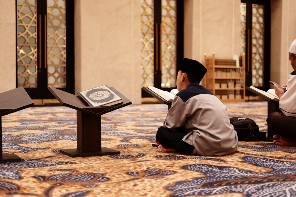 a couple of men sitting on the ground reading books