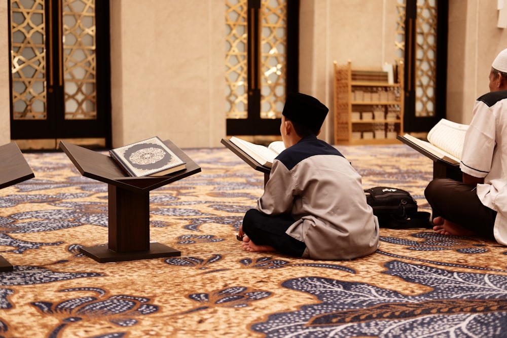 two men sitting on the floor reading books