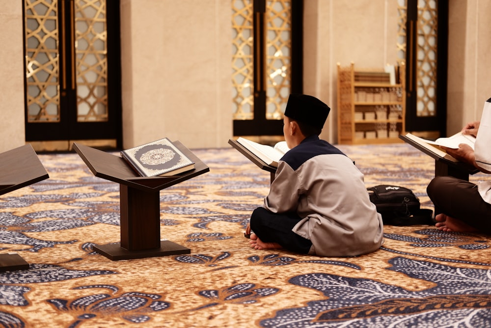 two men sitting on the floor reading books