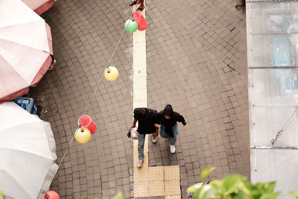 a couple of people walking down a street next to umbrellas