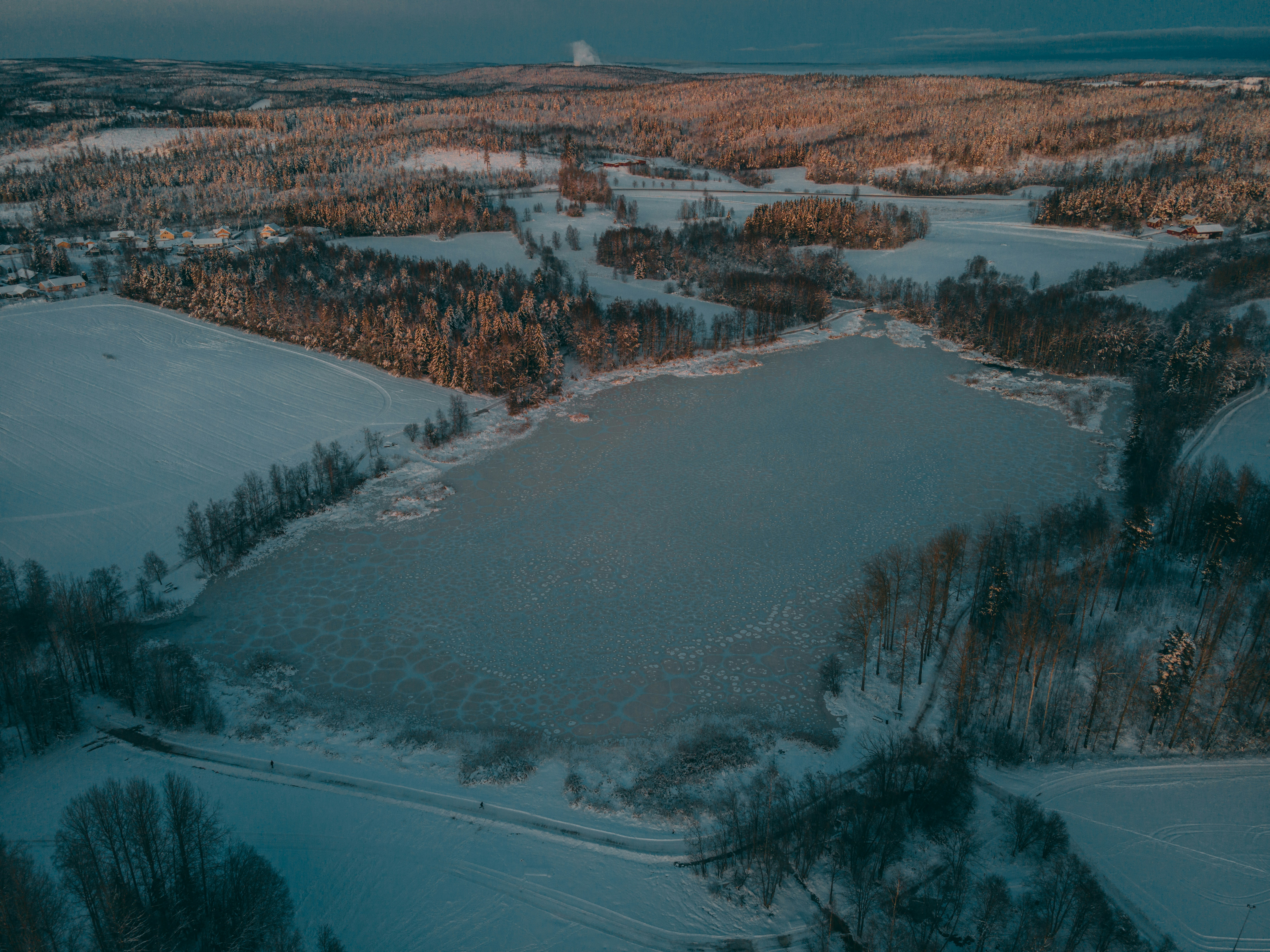 an aerial view of a frozen lake surrounded by trees