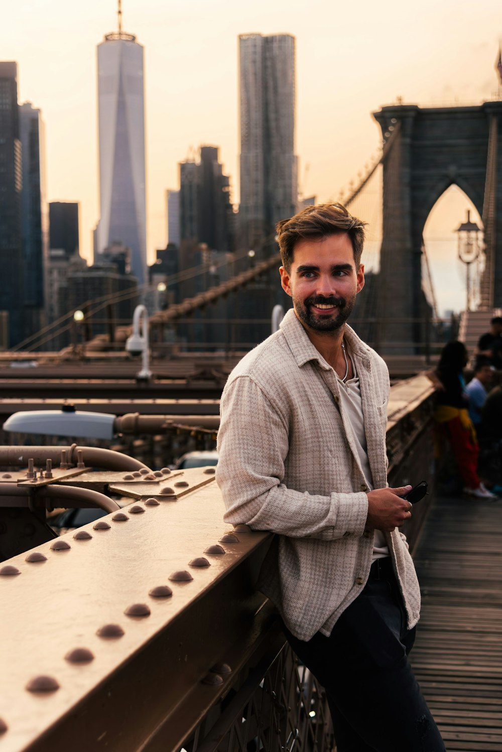 a man standing on a bridge with a city in the background