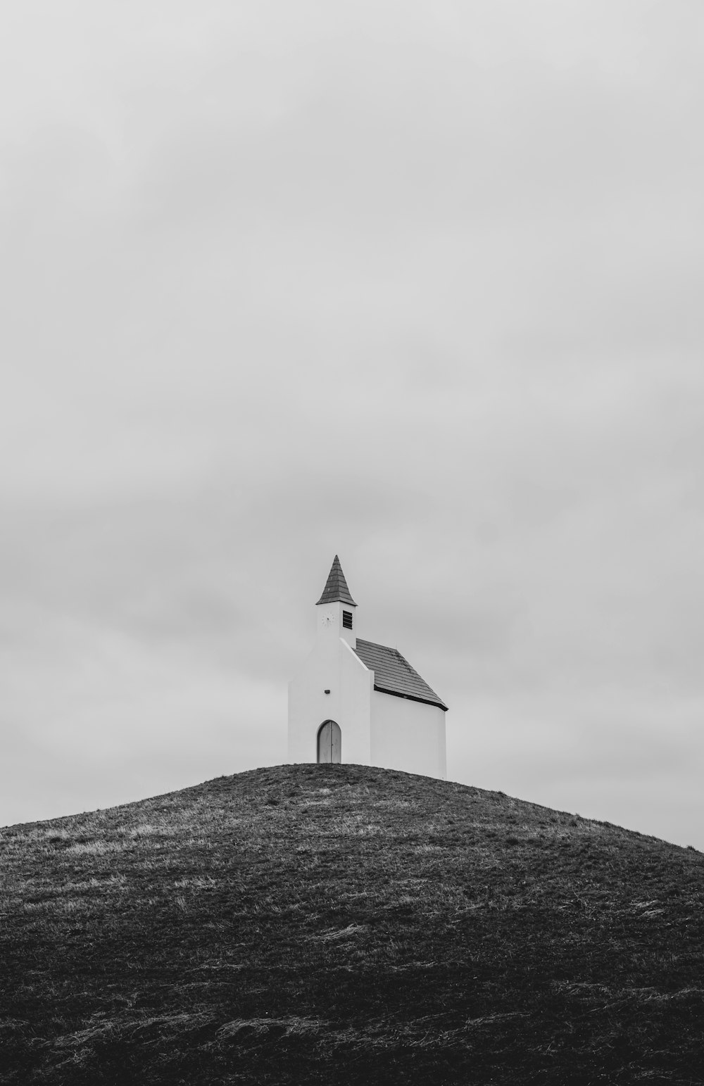 a black and white photo of a church on a hill