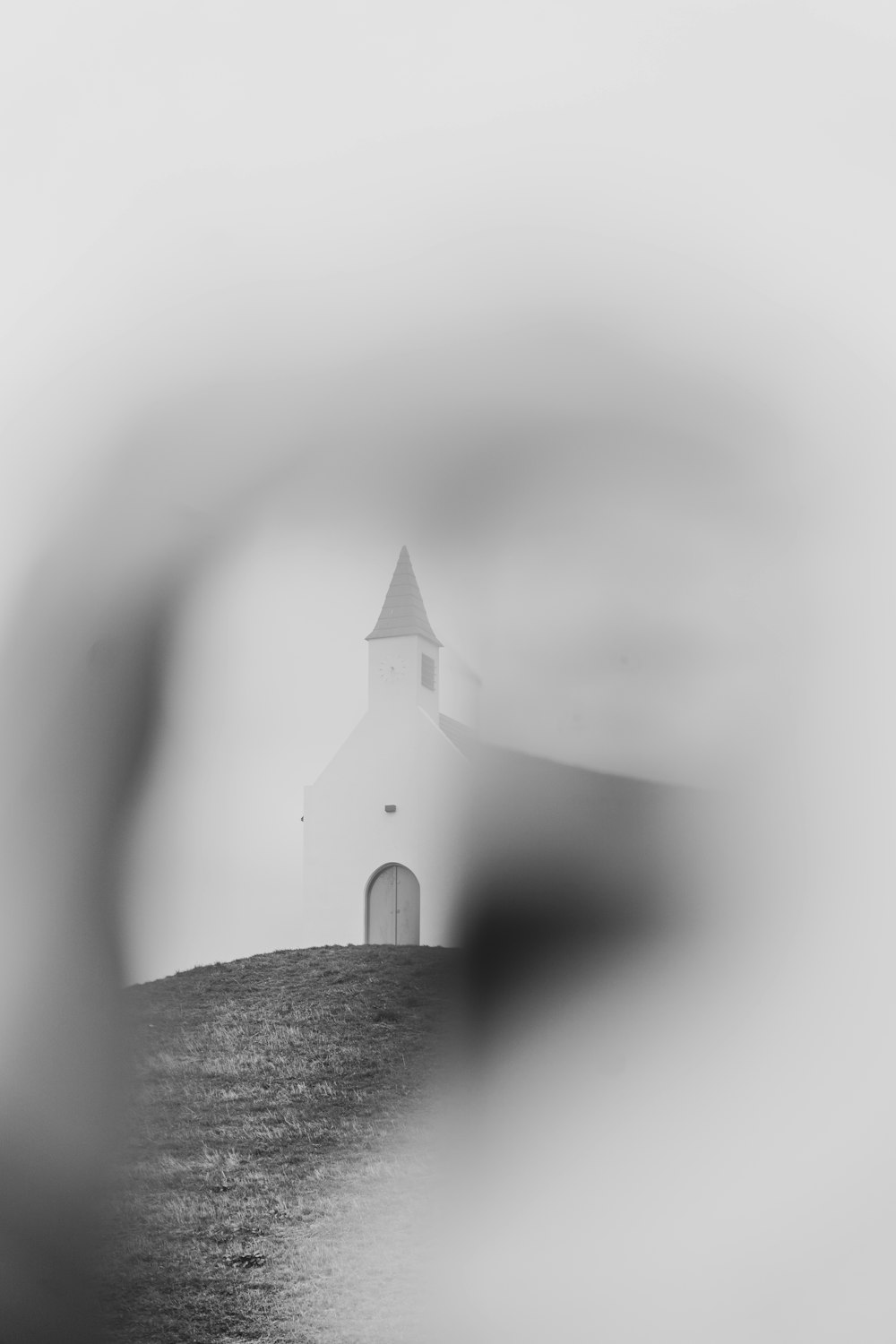 a black and white photo of a church on a hill