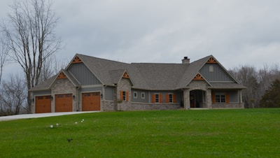 a large house with two garages on a grassy hill
