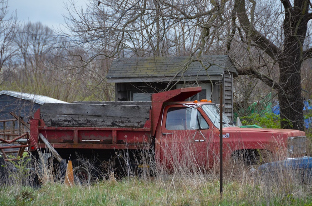 an old red truck is parked in a field