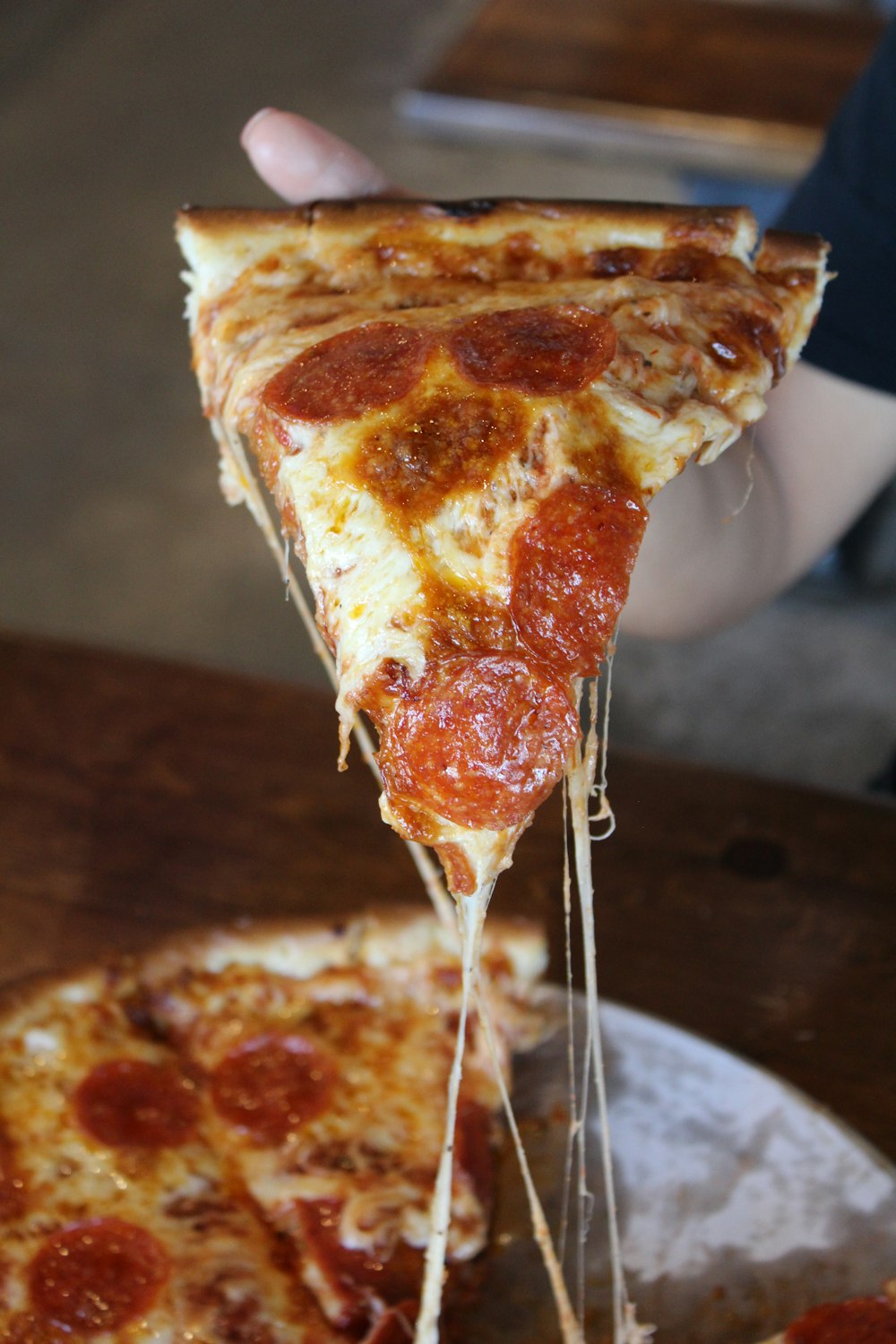 a slice of pepperoni pizza being lifted from a plate