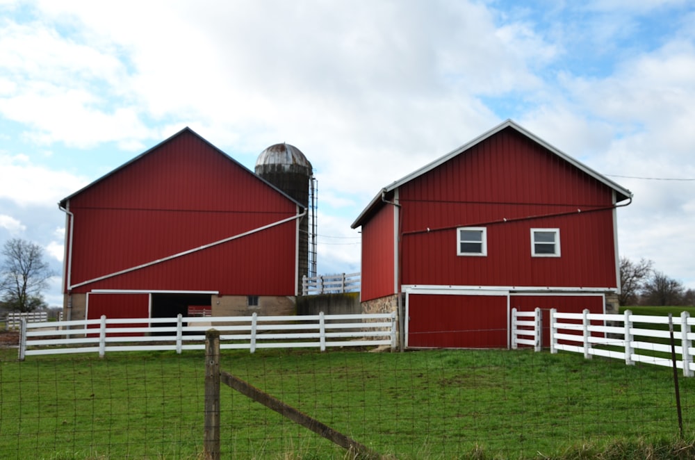 a farm with two red barns and a white fence