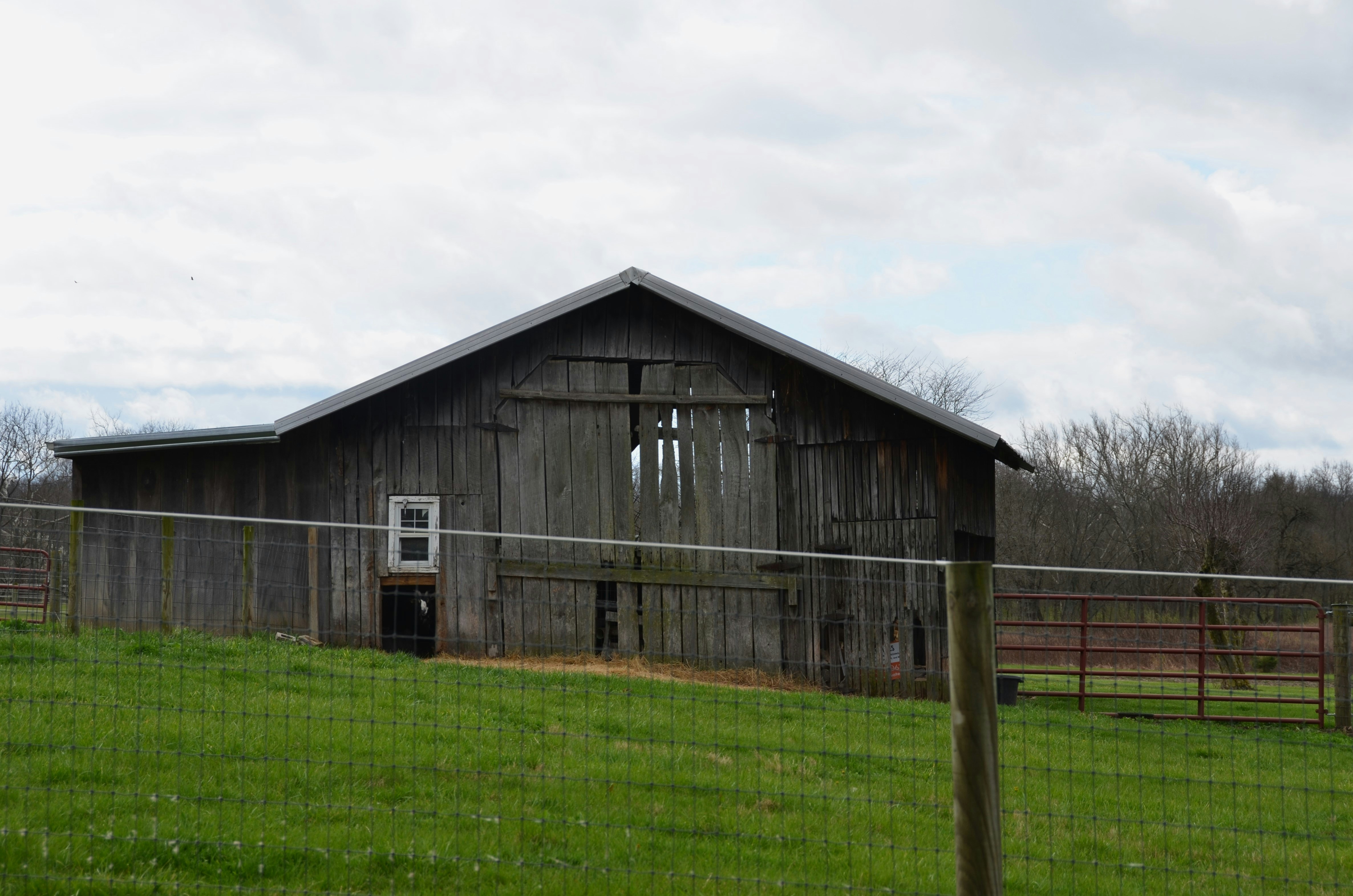 A barn in a field behind a fence