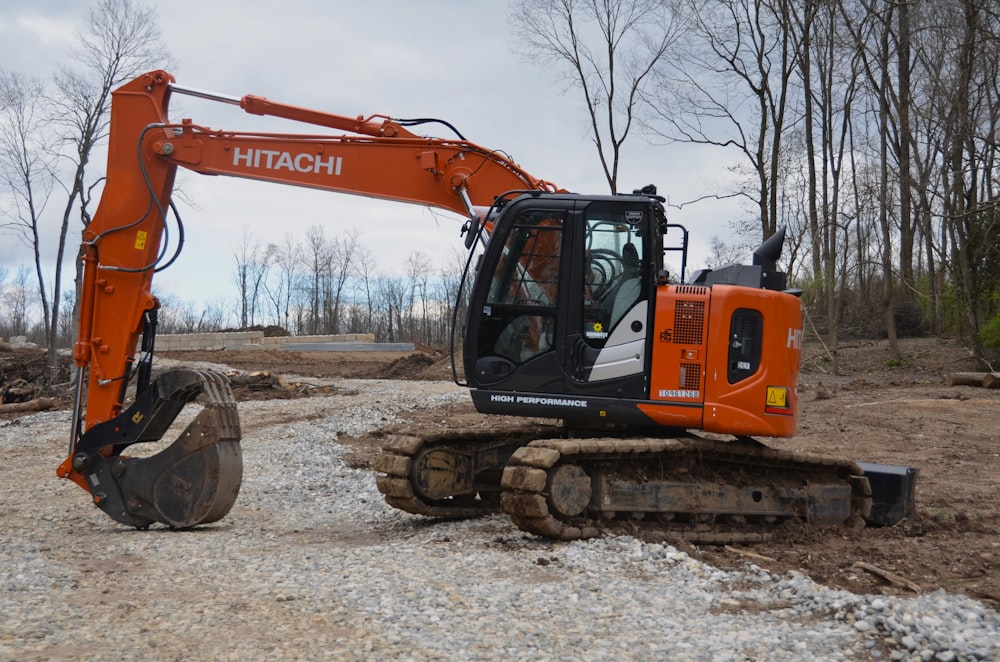 an orange excavator sitting on top of a pile of dirt