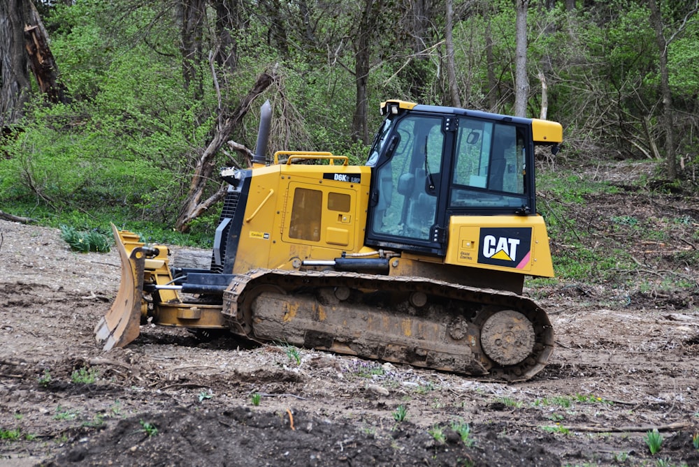 a yellow bulldozer sitting in the middle of a forest