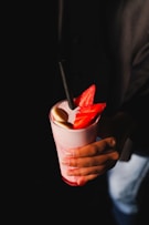 a person holding a drink with strawberries in it