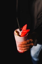a person holding a drink with strawberries in it