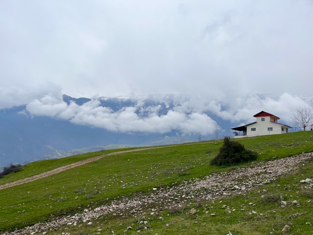 una casa en una colina cubierta de hierba con montañas al fondo