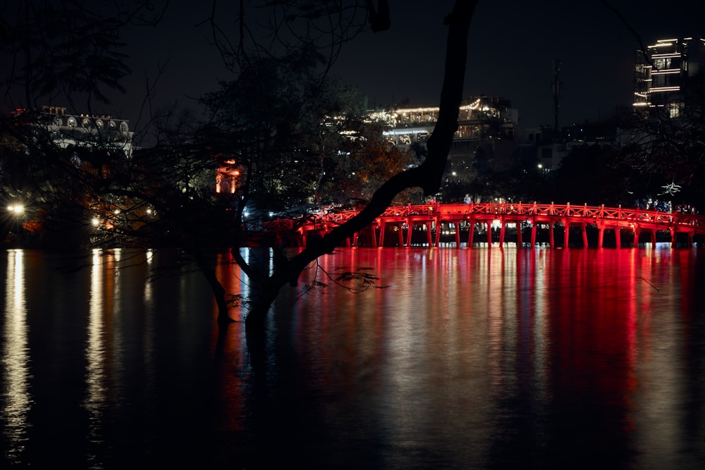 a red bridge over a body of water at night