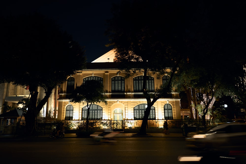 a car driving past a large building at night