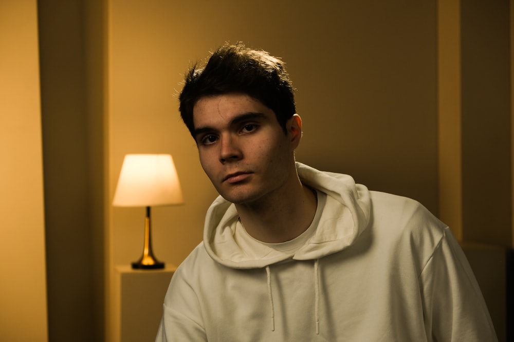 a man in a white hoodie standing in front of a lamp