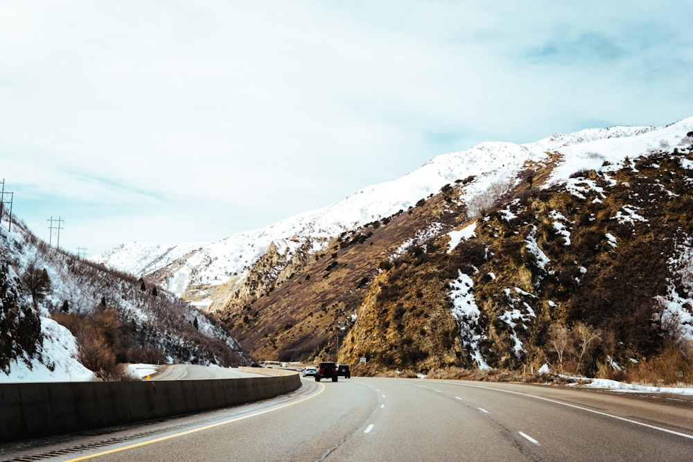 a car driving down a road next to a mountain