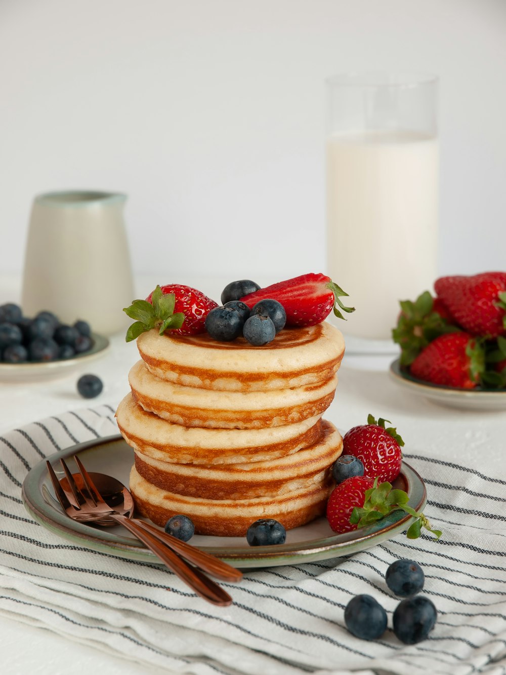 a stack of pancakes with strawberries and blueberries on a plate