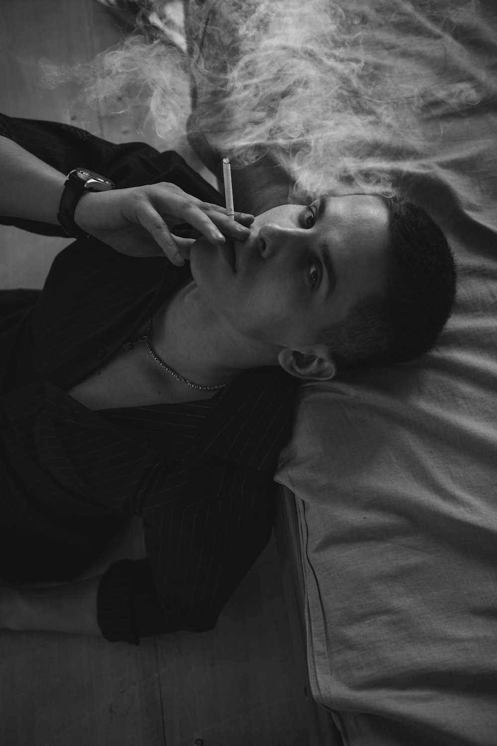 a woman laying on a bed smoking a cigarette