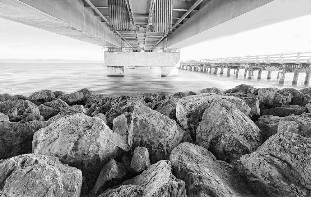 Una foto en blanco y negro de rocas debajo de un puente