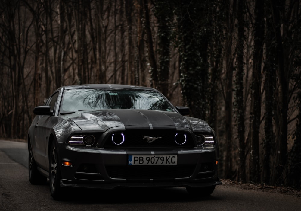 a black mustang parked on the side of a road
