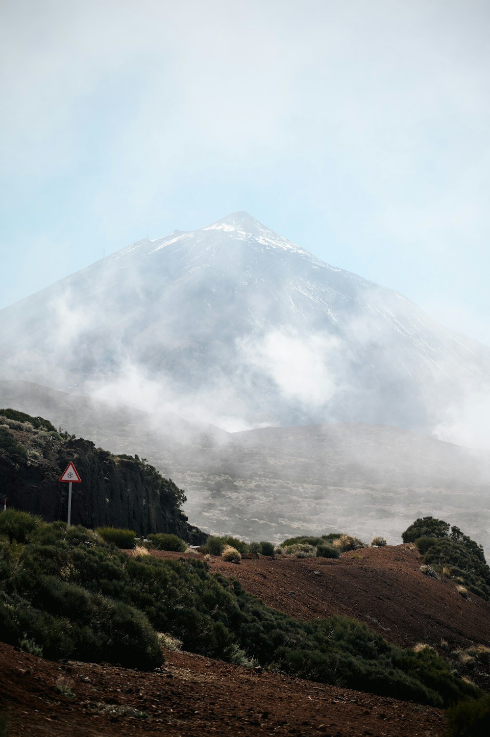 a very tall mountain covered in a cloud filled sky