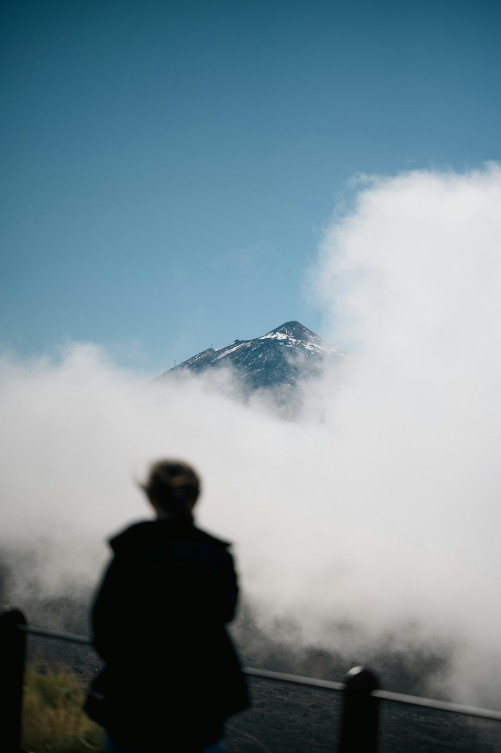 a person standing in front of a mountain covered in clouds