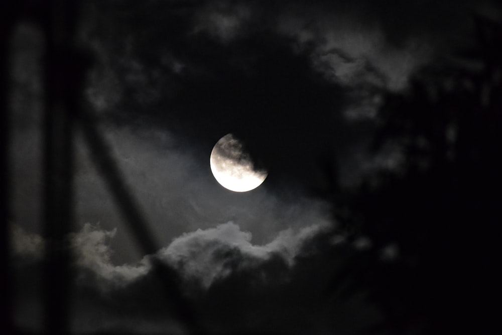 a full moon is seen through the clouds