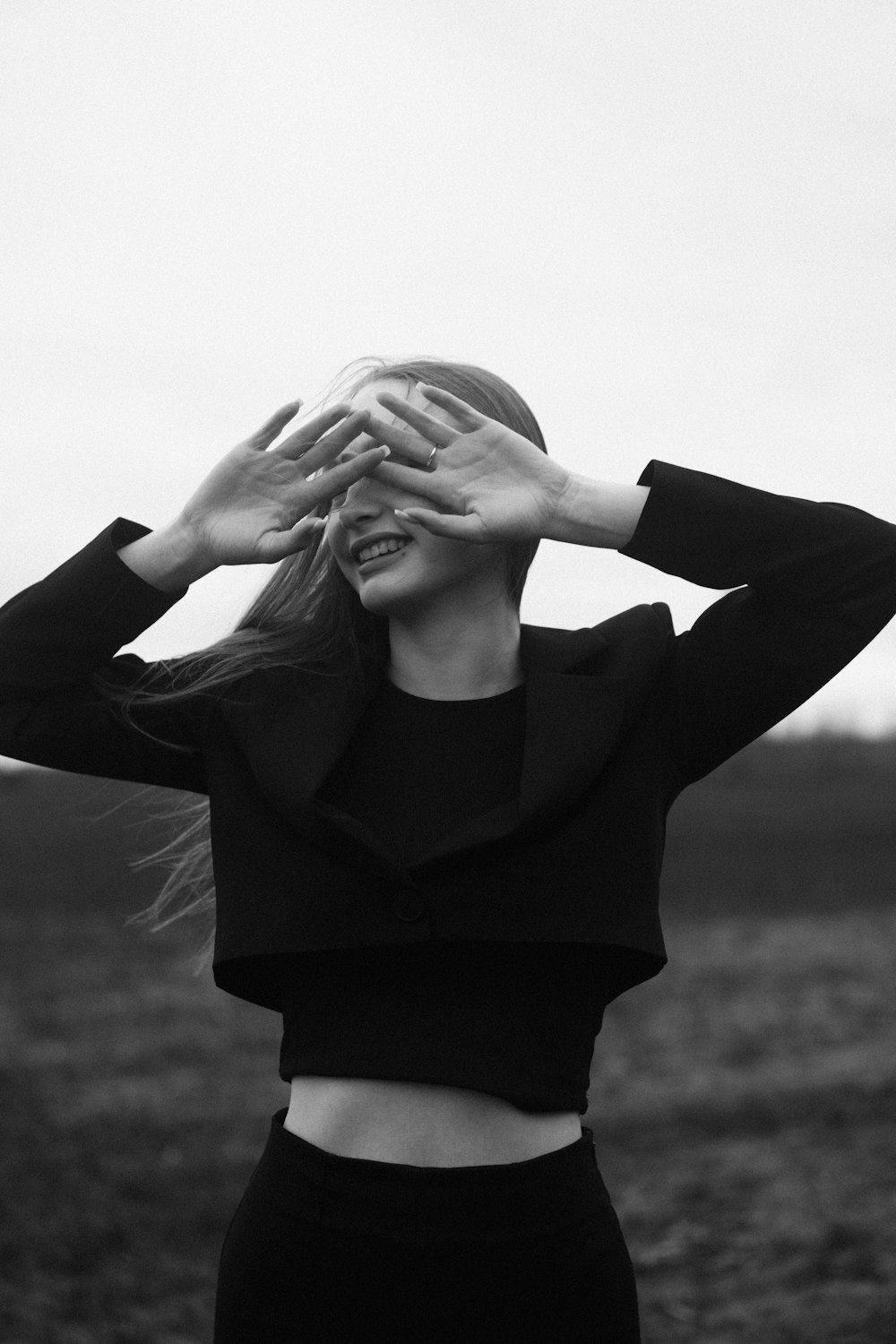 a black and white photo of a woman covering her eyes