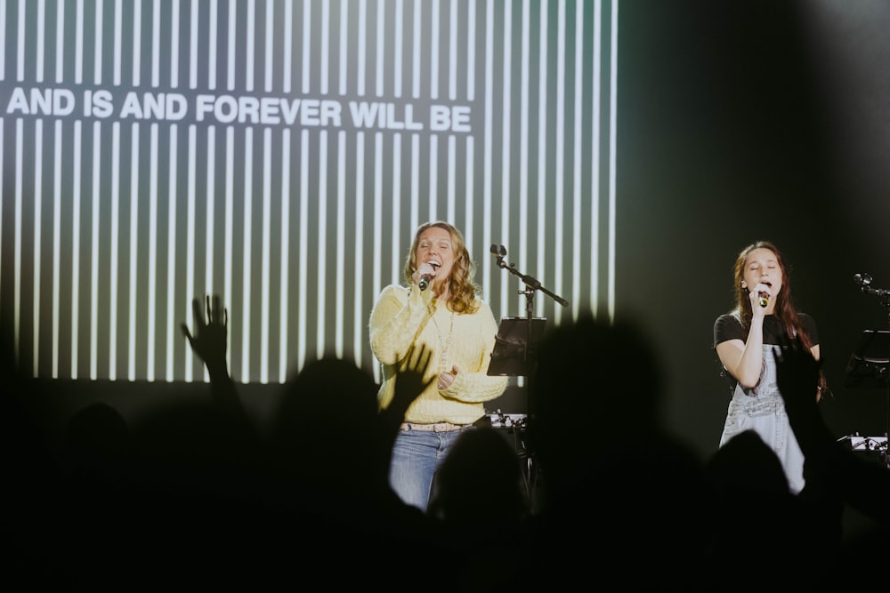 a couple of women standing on top of a stage