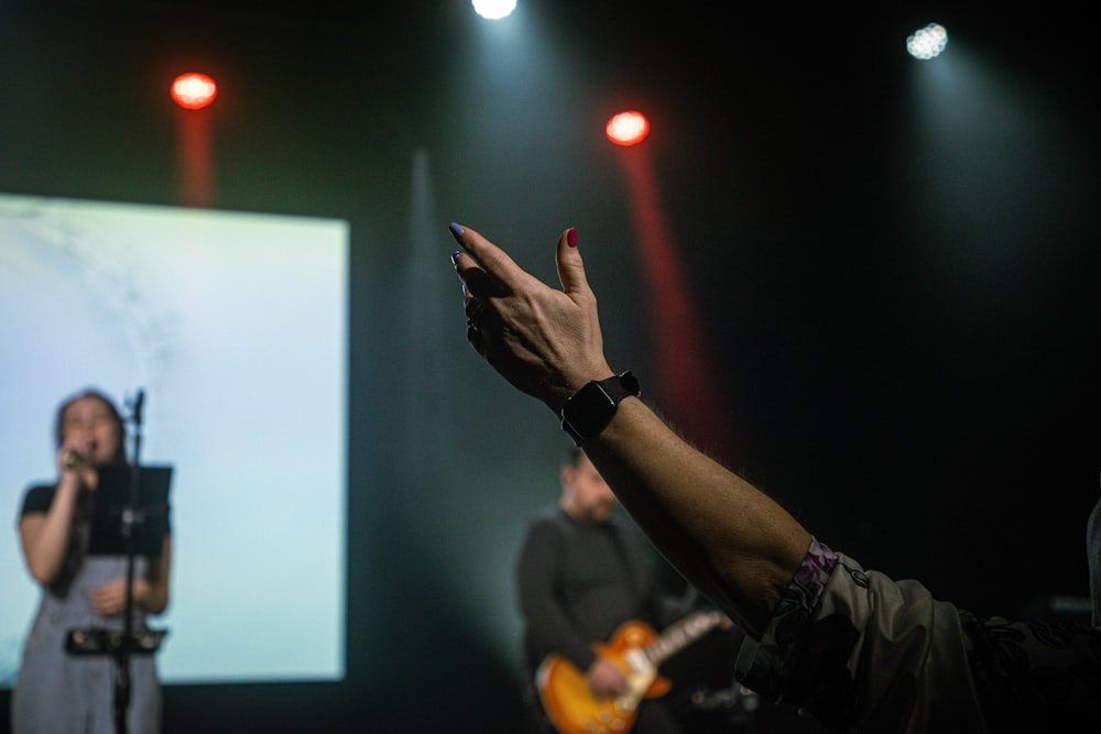 a man holding his hand up in front of a projector screen