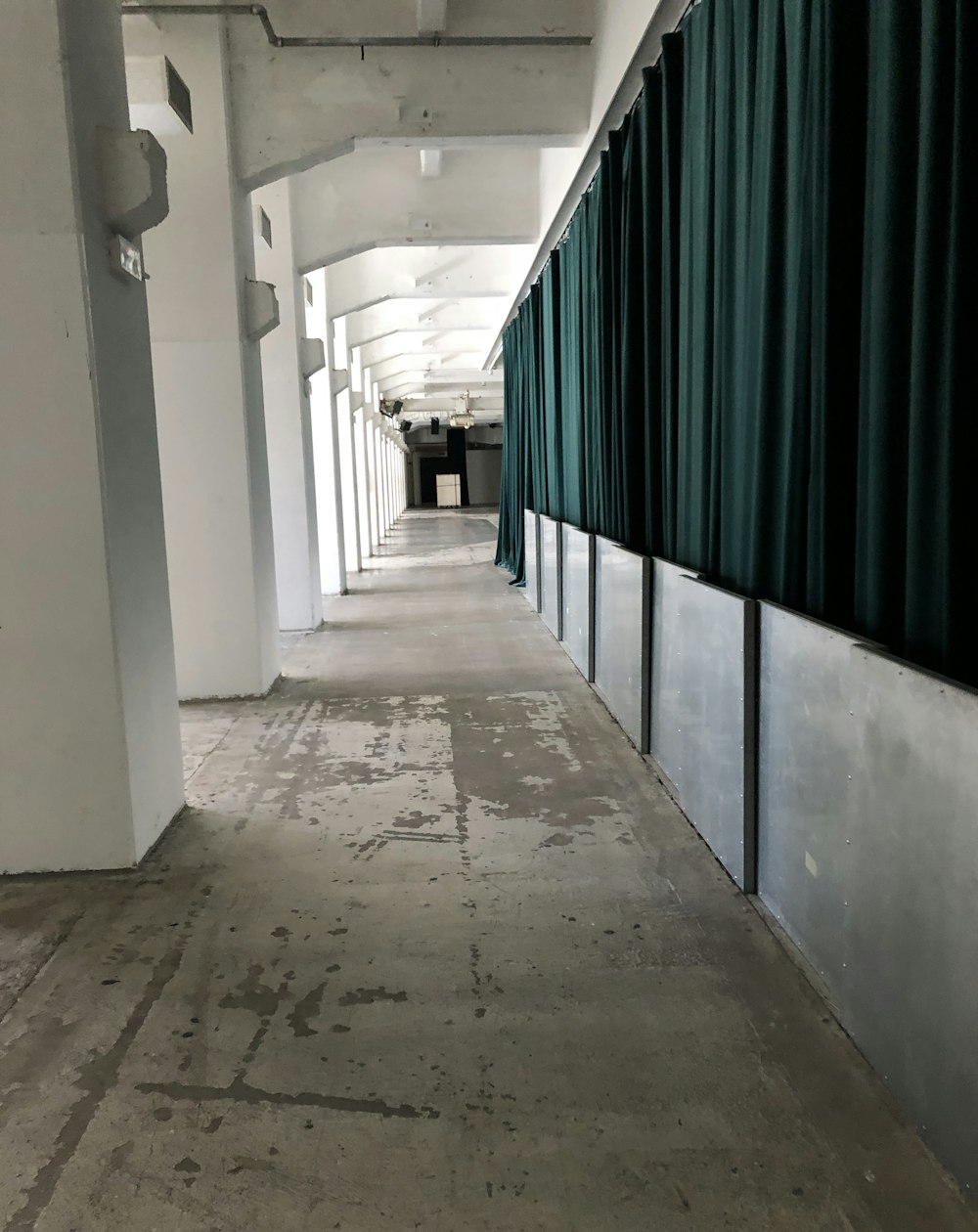 a long hallway with green curtains on the side of it