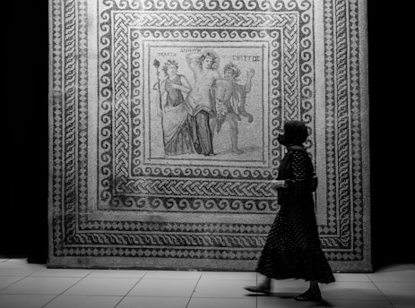 a woman walking past a wall with a painting on it