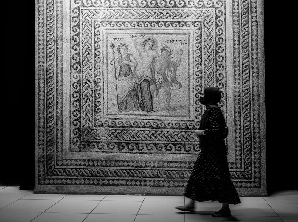 a woman walking past a wall with a painting on it
