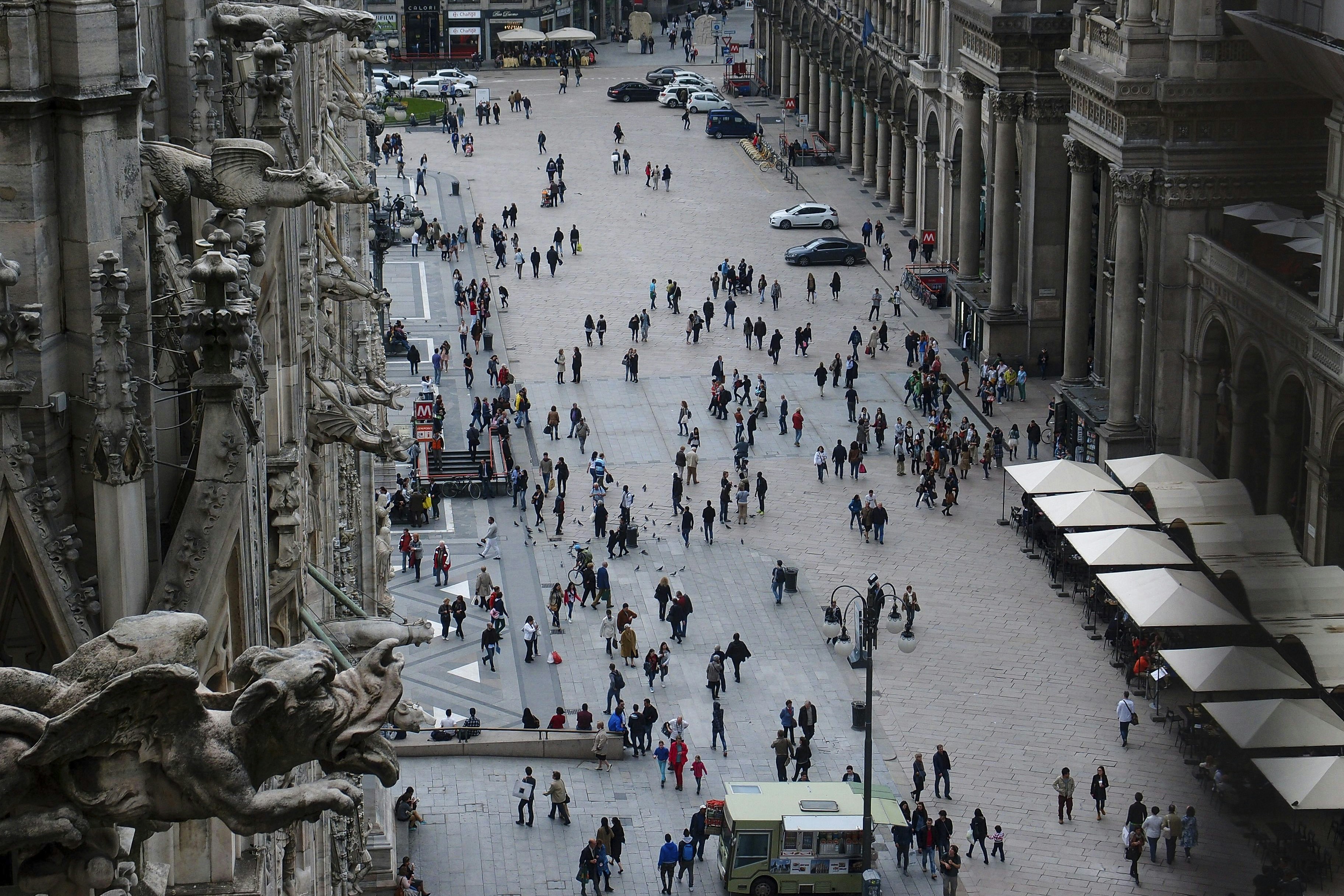 a group of people walking down a street next to tall buildings