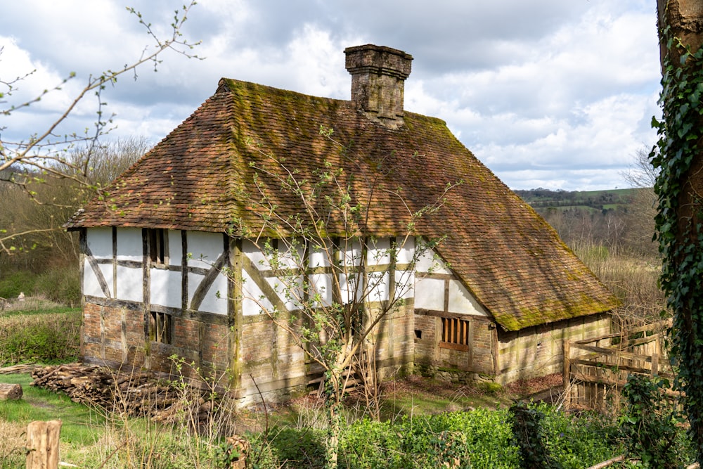an old house with a thatched roof in a field