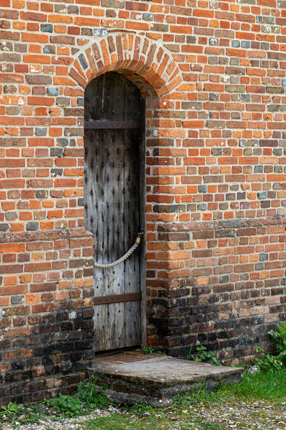 a brick wall with a wooden door and a rope