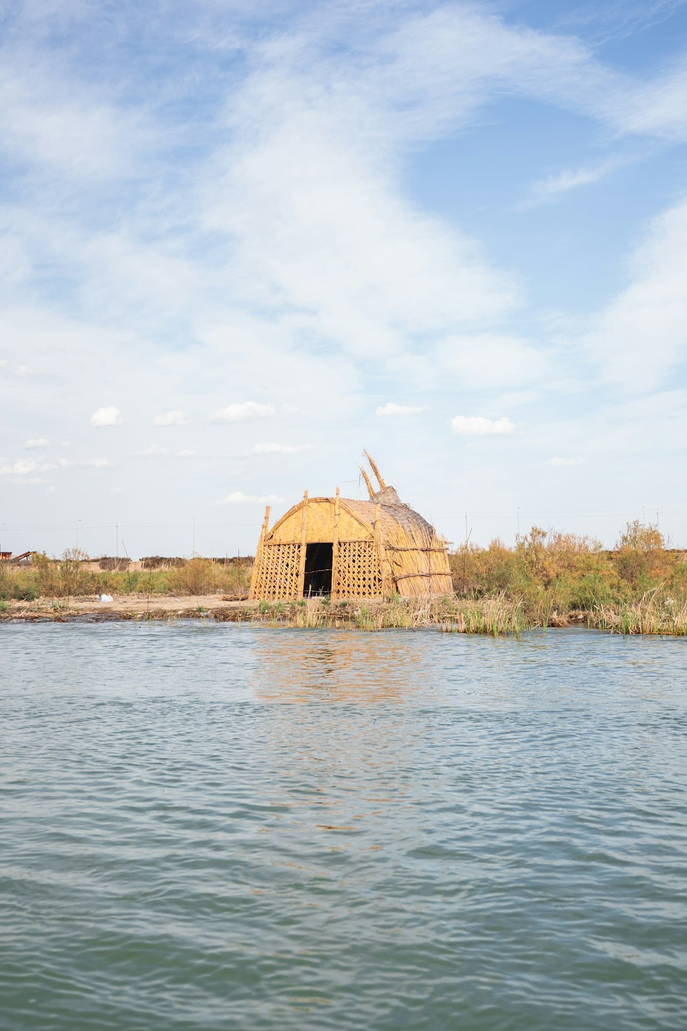a house made out of straw sitting on top of a lake