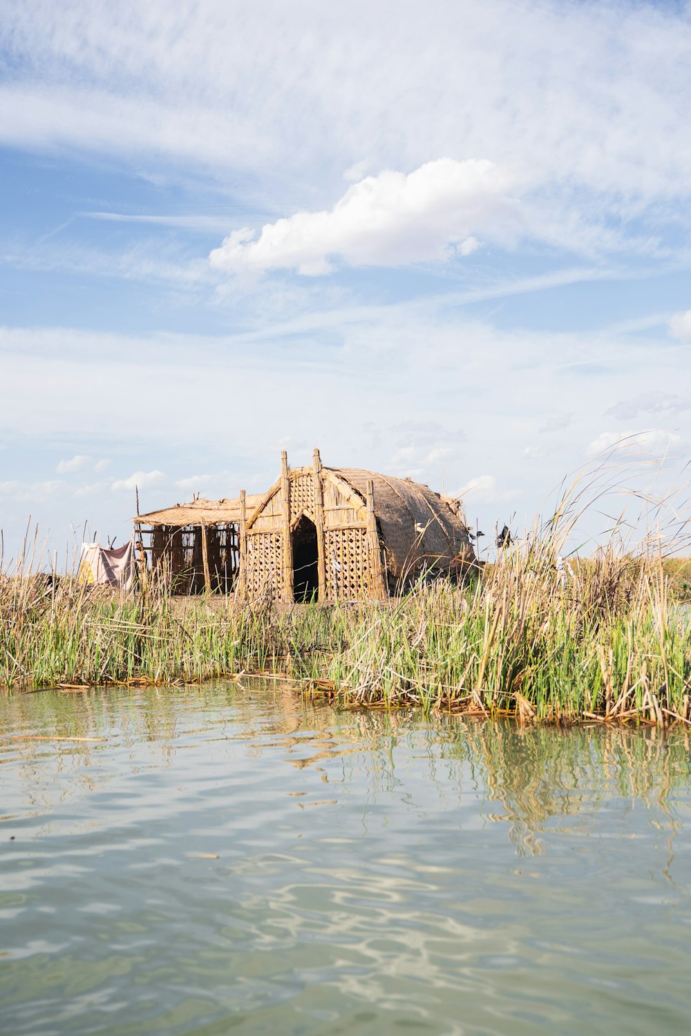 a hut is sitting on the shore of a lake