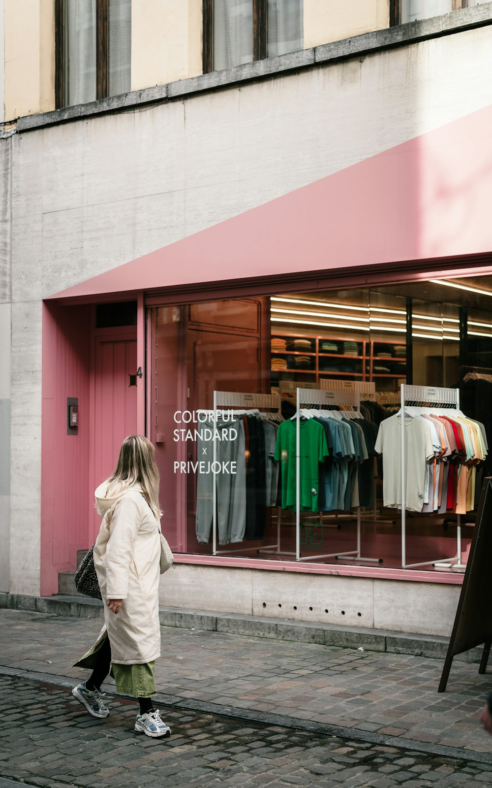 a woman walking down a street past a clothing store