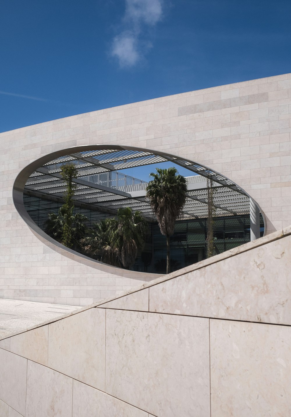 a building with a circular window and palm trees in front of it